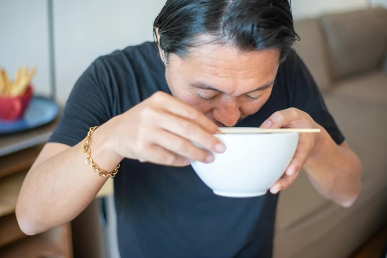 a man is eating with a white bowl