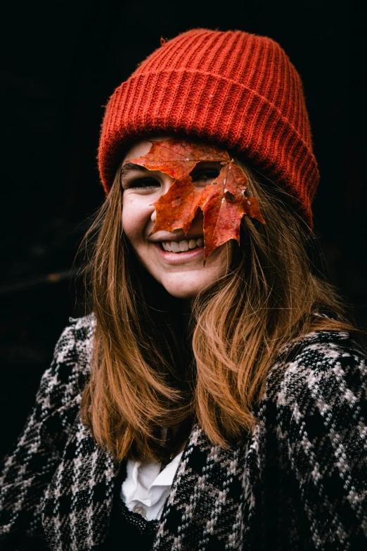 a woman with a leaf on her face, pexels contest winner, red hat, smiling into the camera, 🍂 cute, broken mask