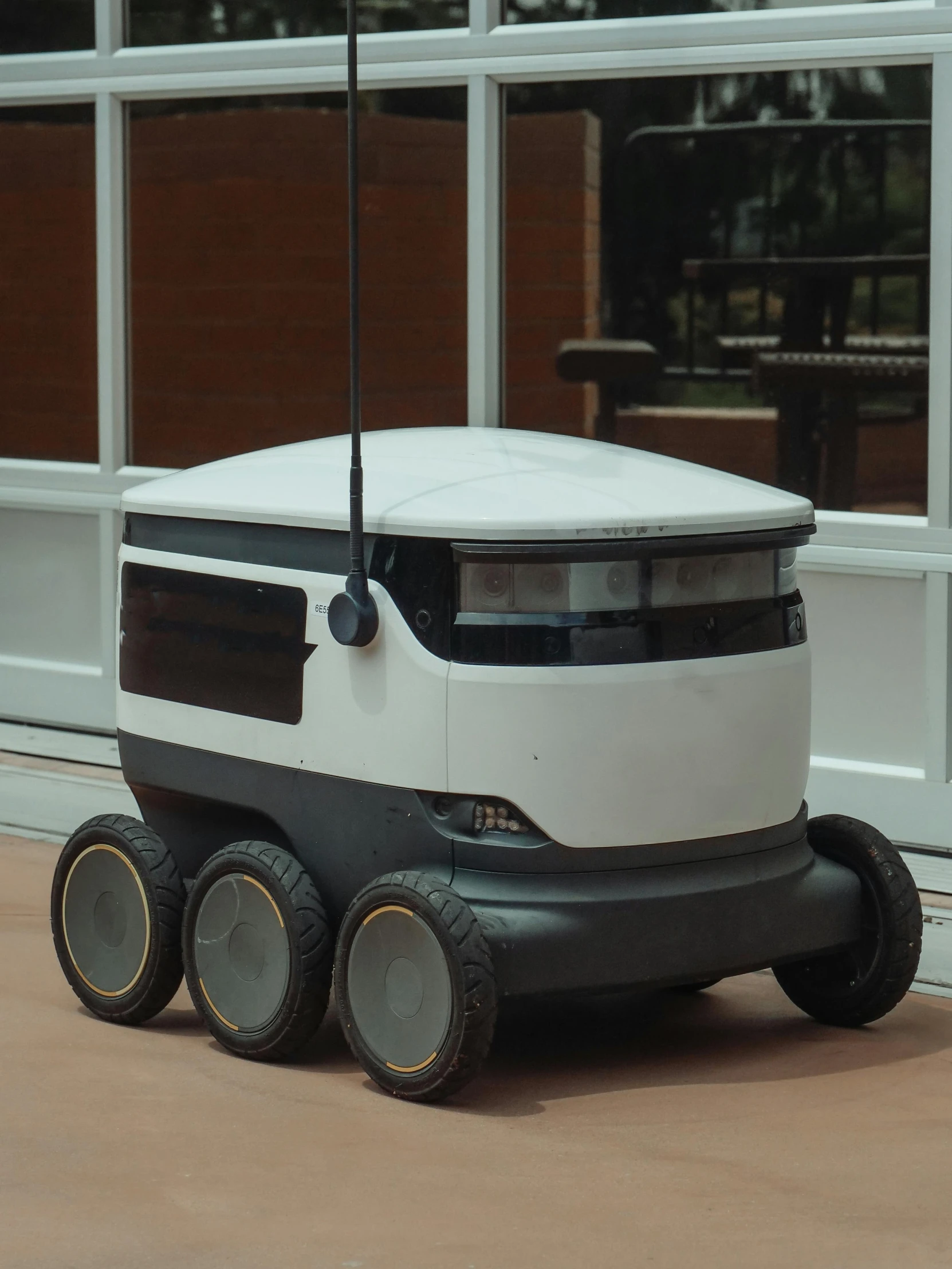 a white and black robot sitting in front of a building