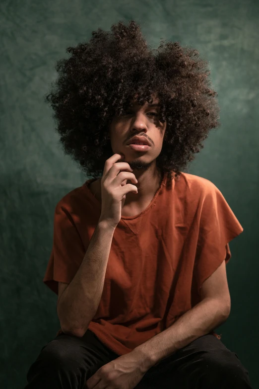 a man sitting on a stool with his hand on his chin, an album cover, by Charles Martin, pexels contest winner, curly bangs, brown skin man egyptian prince, headshot profile picture, teenage boy