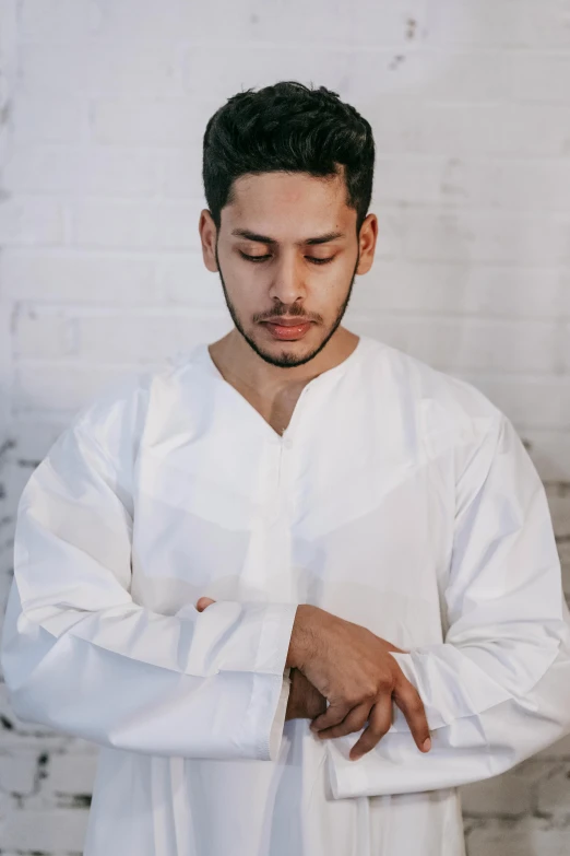 a man in white robe holding his hands in prayer position