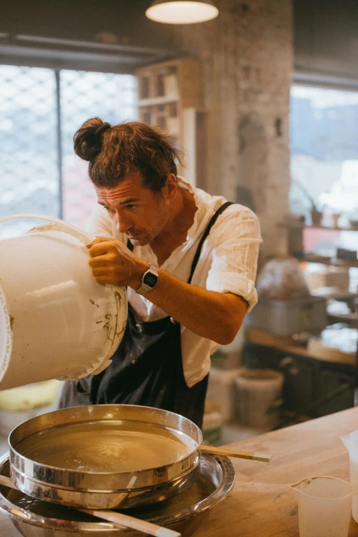 a woman pouring milk into a pot in a kitchen, a portrait, trending on unsplash, process art, handsome man, dough sculpture, in australia, in a workshop