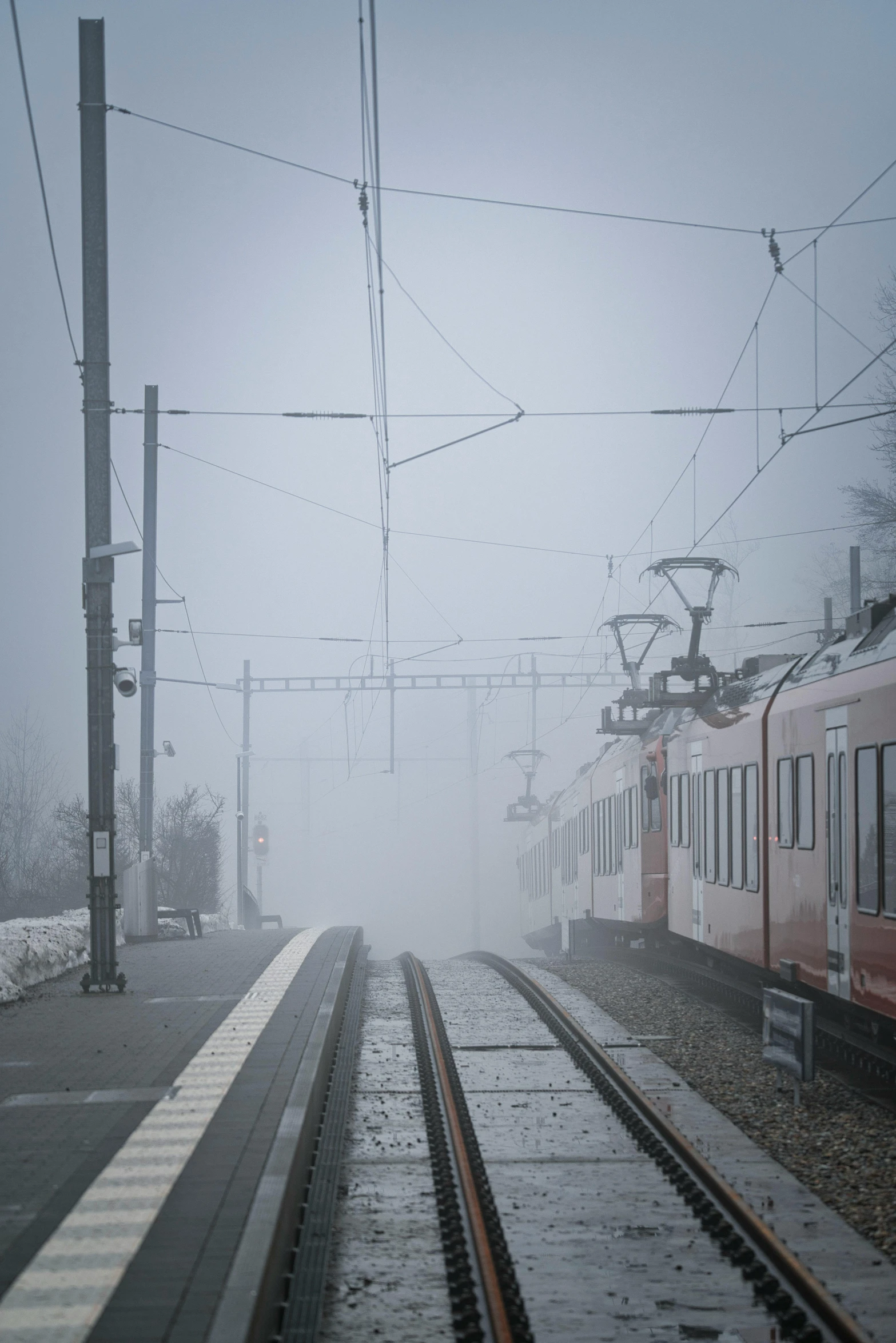 a train traveling down train tracks on a foggy day, by Jens Søndergaard, town in the background, chairlifts, freezing, high quality photo