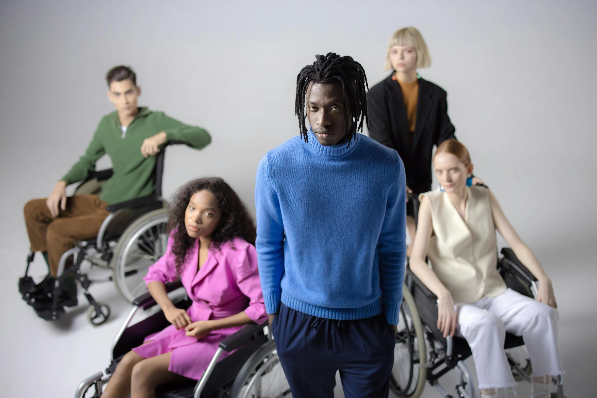 a group of people in wheelchairs posing for a picture, an album cover, by Carey Morris, trending on pexels, blue turtleneck, yasuke 5 0 0 px models, at a fashion shoot, coloured