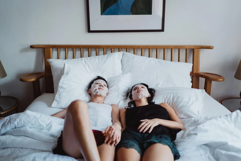 two women are sitting in bed with their faces painted