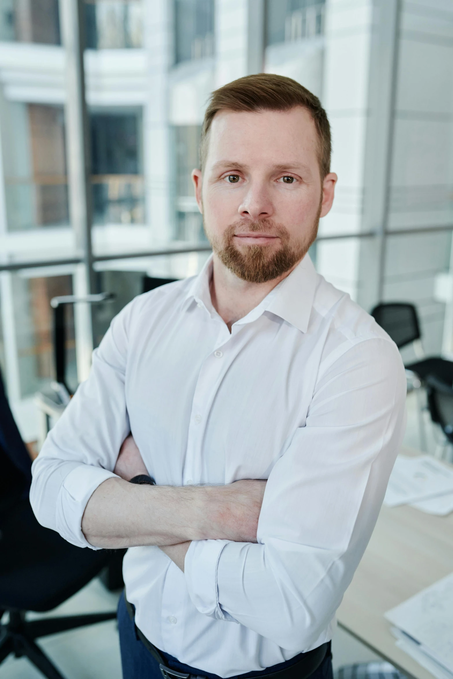 man in white shirt with his arms crossed in an office setting