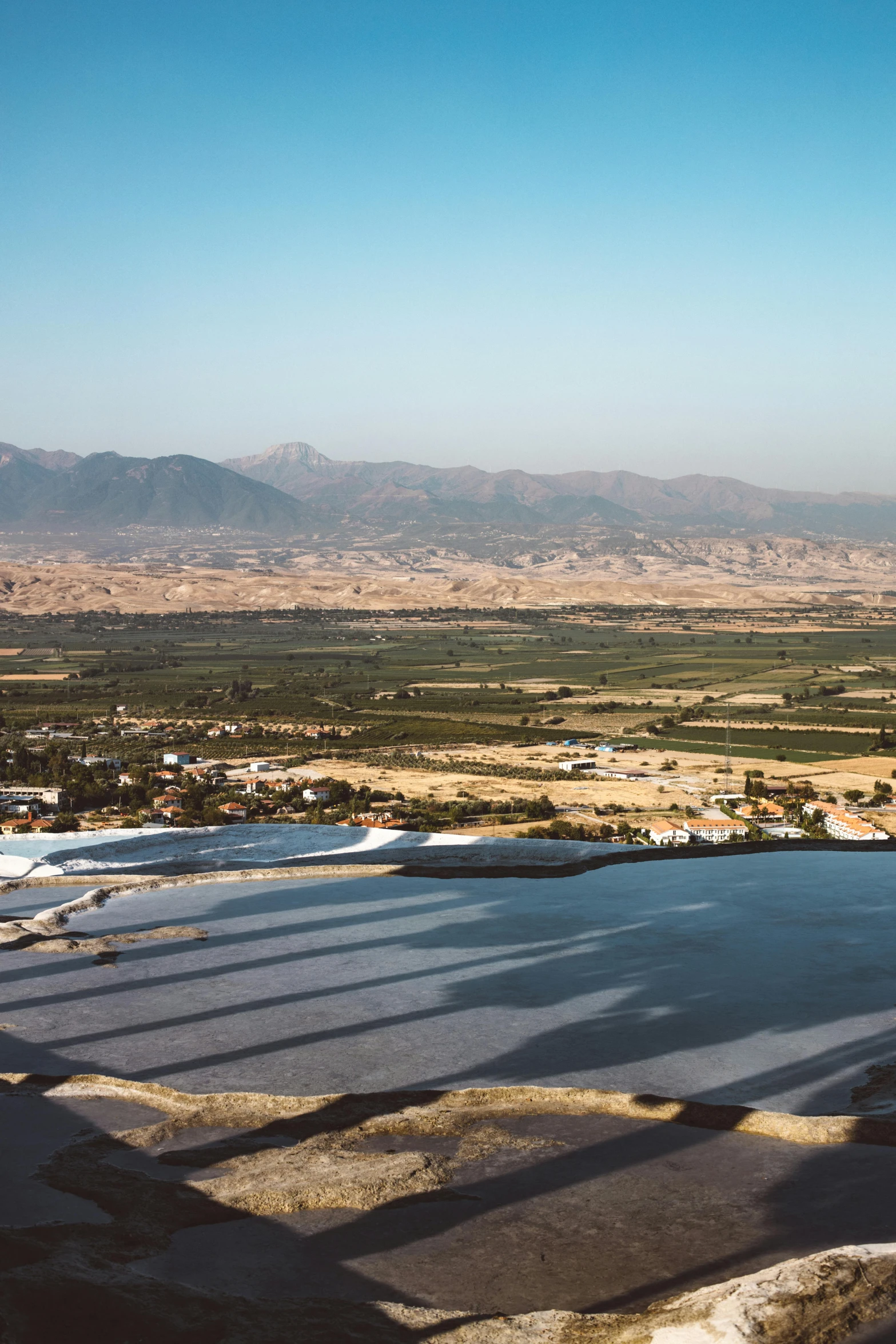 an aerial view of a large body of water, by Juan Giménez, les nabis, terraced orchards and ponds, distant mountains, sitting atop a dusty mountaintop, expansive cinematic view