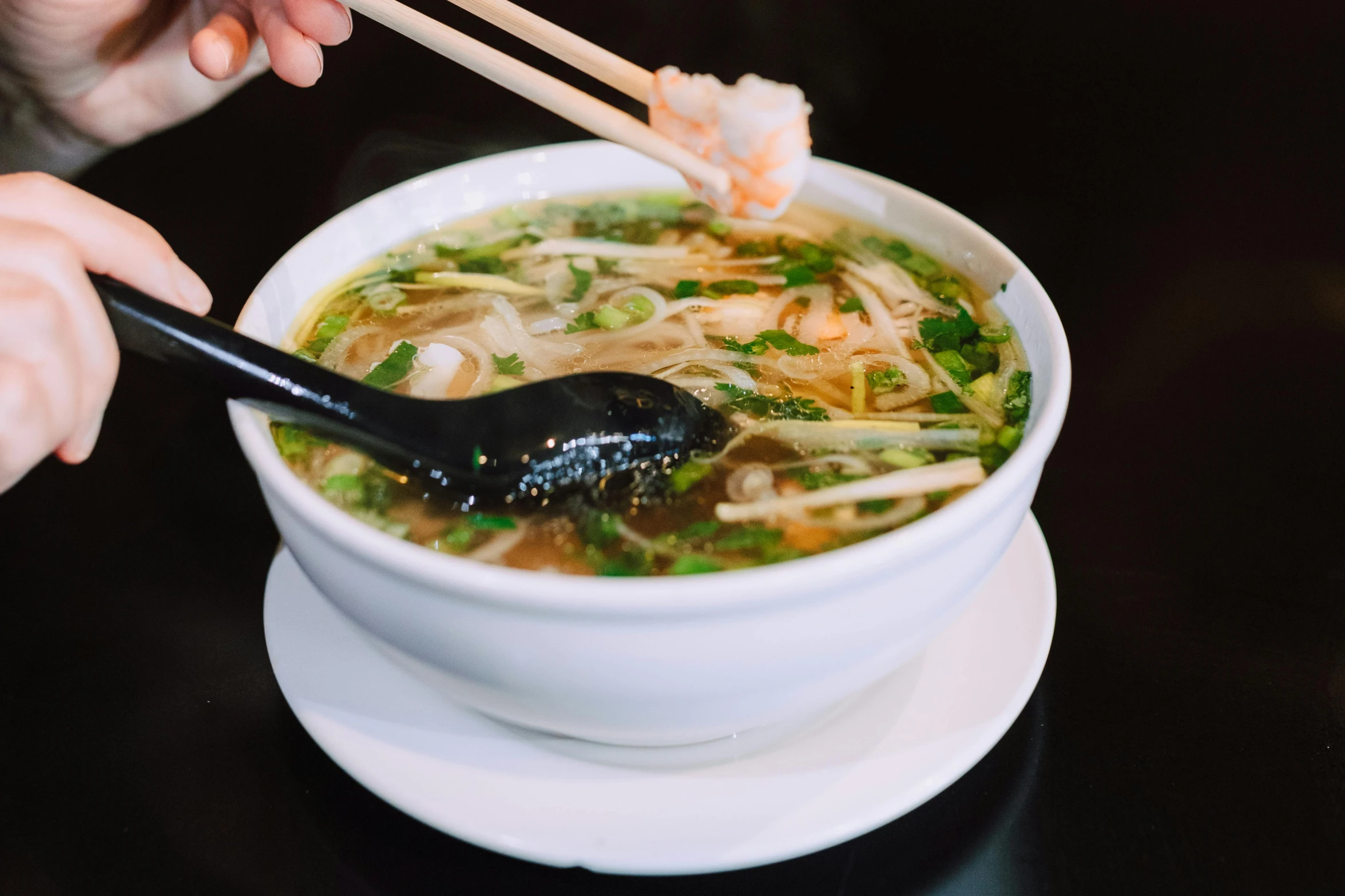 a person eating a bowl of soup with chopsticks, daily specials, square, prawn, wet boody