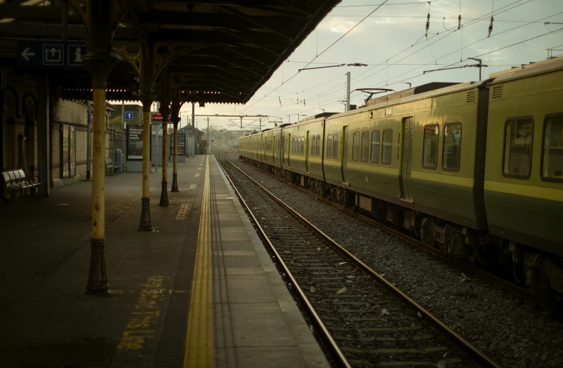 a yellow train pulling into a train station, a picture, by Anna Findlay, unsplash, wide film still, caulfield, green lights, tan