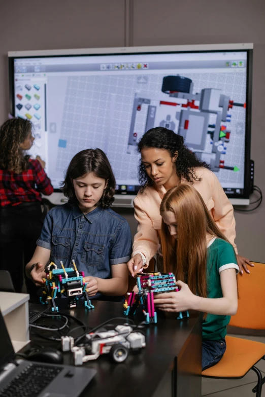 a group of people standing around a table with legos, a digital rendering, trending on pexels, american barbizon school, portrait of computer & circuits, high school girls, led displays, bionicle