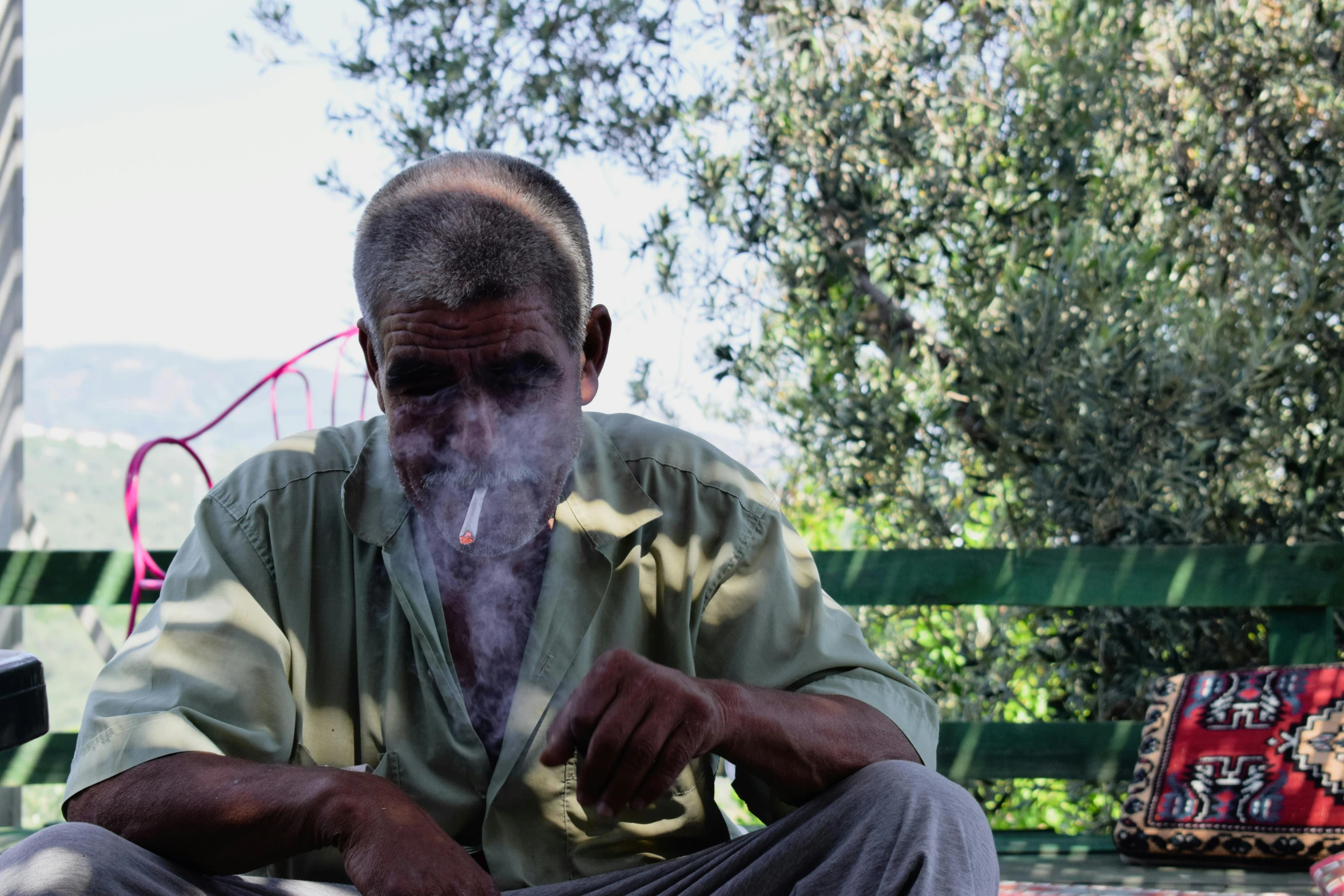 a man sitting on a bench smoking a cigarette, dirty olive skin, video still, farmer, profile image