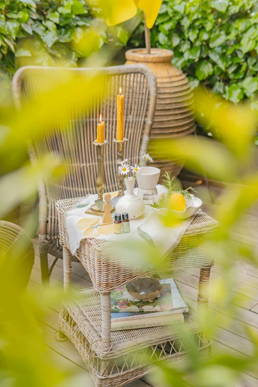 a wicker chair and table outside with a lantern on top