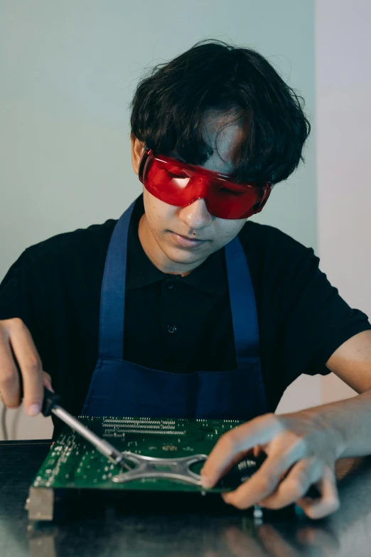 a man in a blindfold working on a circuit board, an album cover, inspired by Yasutomo Oka, pexels contest winner, renaissance, thin young male alchemist, superhero, mit technology review, red hot soldering iron