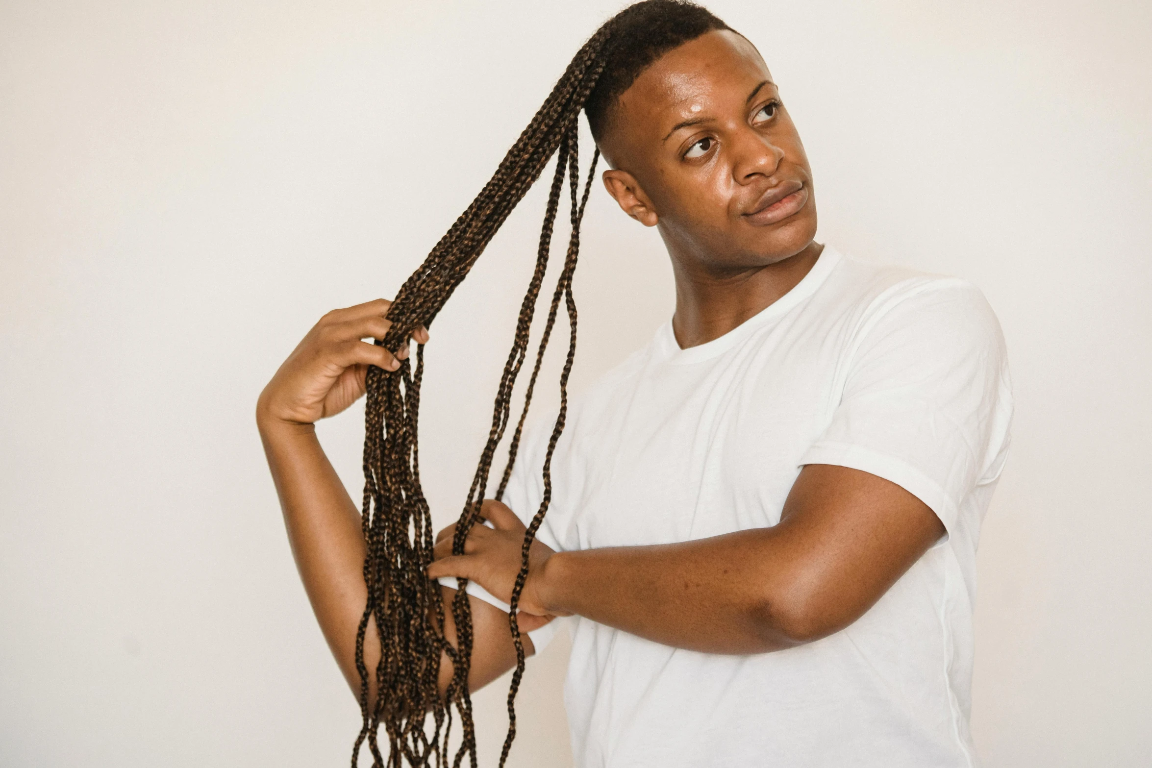 a man wearing a white shirt and braiding his hair, inspired by Theo Constanté, pexels contest winner, les nabis, box braids, in front of white back drop, detailed product image, natural tpose