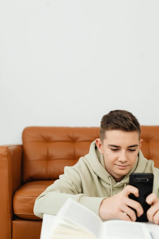 a man sitting on a couch looking at a cell phone, trending on pexels, teenage boy, avatar image, brown, high school