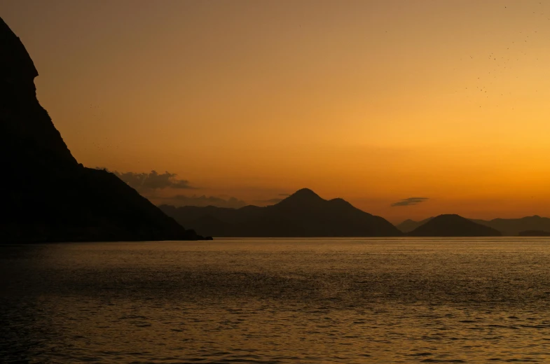 a large body of water with mountains in the background, by Exekias, pexels contest winner, romanticism, orange lit sky, kowloon, conde nast traveler photo, fan favorite