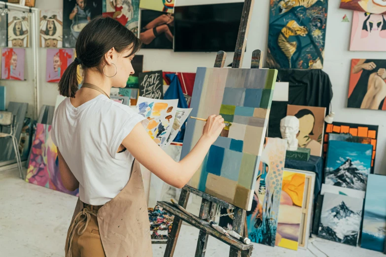 a woman standing in front of a painting on a easel, trending on pexels, academic art, oil paint impasto reliefs, artist wearing overalls, ilustration, various artworks