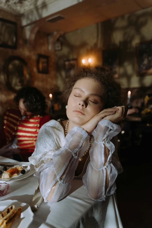 a woman sitting at a table with her hand on her head