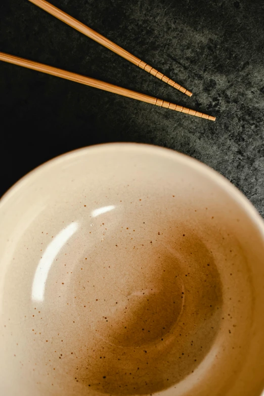 a close up of a bowl with chopsticks in it, a portrait, inspired by Maruyama Ōkyo, trending on unsplash, mingei, limestone, saturated top light, brown, 4l