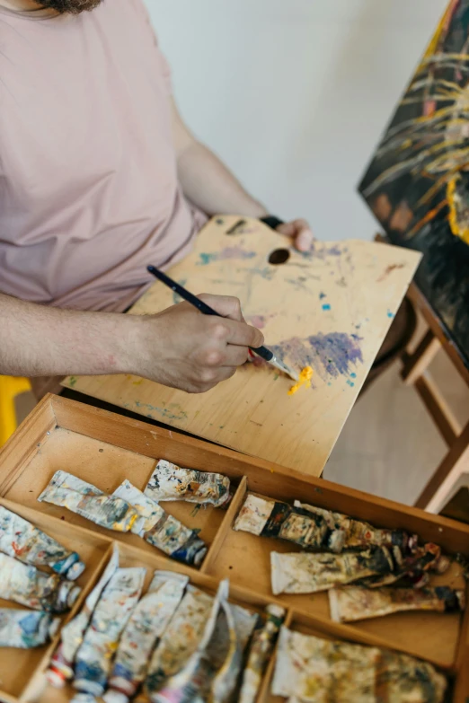 a woman is painting in an artist's studio, trending on pexels, arbeitsrat für kunst, painting of a man, yellow ochre, palette knife, on a white table