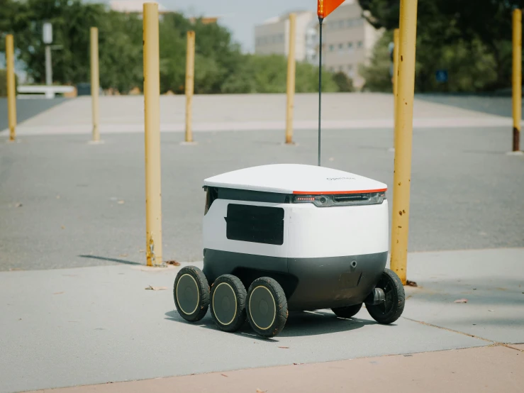 a white robot sitting on top of a sidewalk, cart, square, circular, futuristic product design