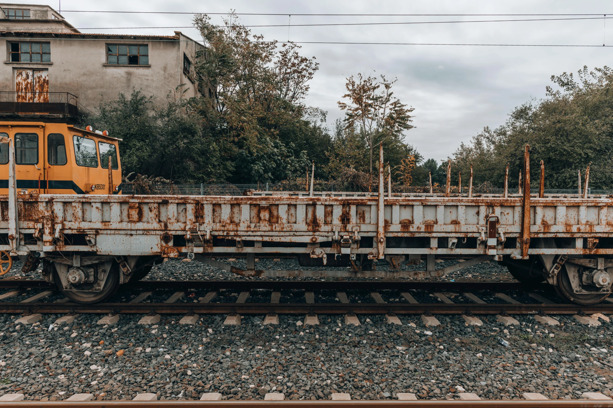 a train traveling down train tracks next to a building, by Attila Meszlenyi, unsplash, rust and plaster materials, 2000s photo, in the yard, vehicle