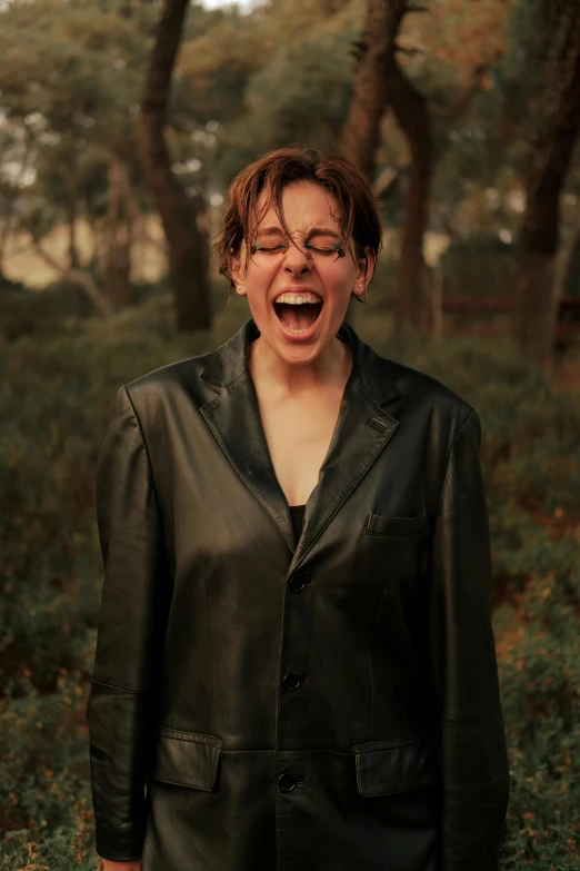 a woman standing in a field with her mouth open, an album cover, inspired by Jean Malouel, pexels contest winner, wearing leather coat, ecstatic face expression, wearing a worn out suit, julian ope