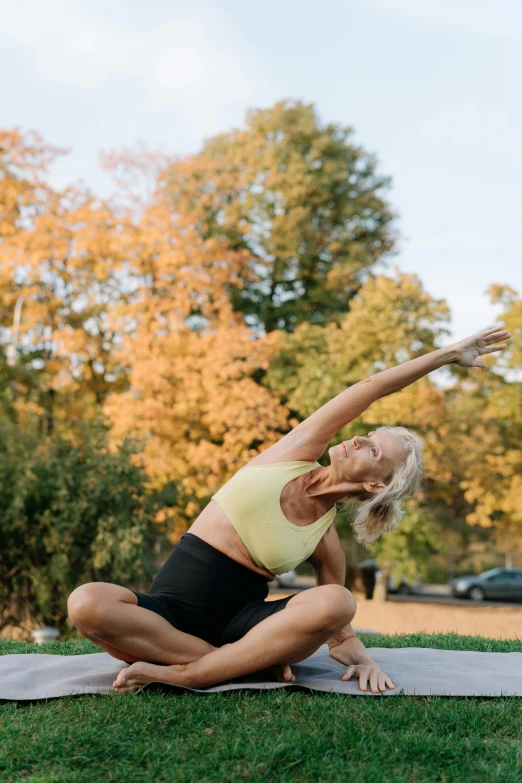 an elderly woman practices yoga on a mat