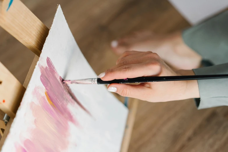 a woman is painting with brush while sitting at a table