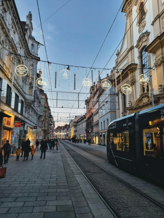 people walking on street next to train with christmas lights