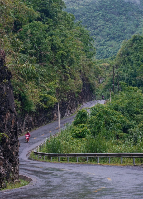 a man riding a motorcycle down a curvy road, philippines, slide show, trees and cliffs, guangjian huang