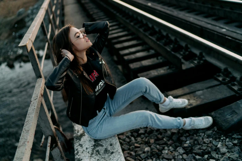 a woman sitting on a rail road track, inspired by Elsa Bleda, pexels contest winner, graffiti, leather jacket and denim jeans, 15081959 21121991 01012000 4k, black, relaxed pose