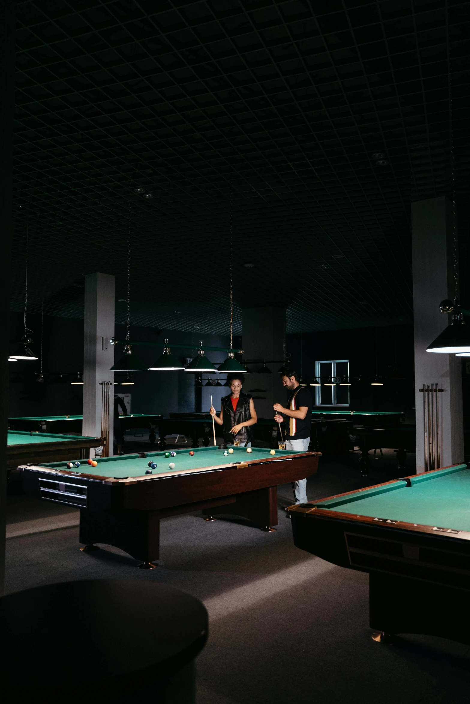 two people sitting on the edge of some pool tables