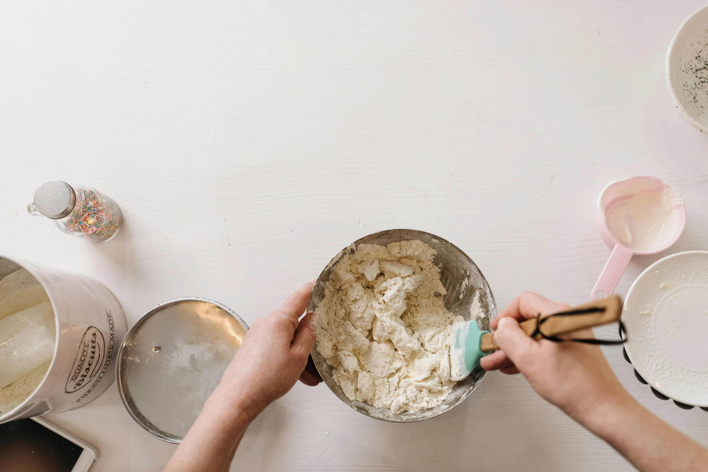 a person mixing ingredients in a bowl on a table, by Ruth Simpson, trending on unsplash, silver，ivory, bakery, background image