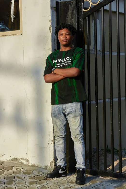 a young man stands against a wrought iron fence