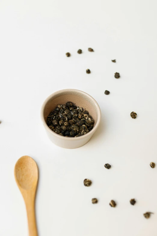 a bowl of black pepper next to a wooden spoon, inspired by Hasegawa Tōhaku, tiny stars, curated collections, green tea, snail