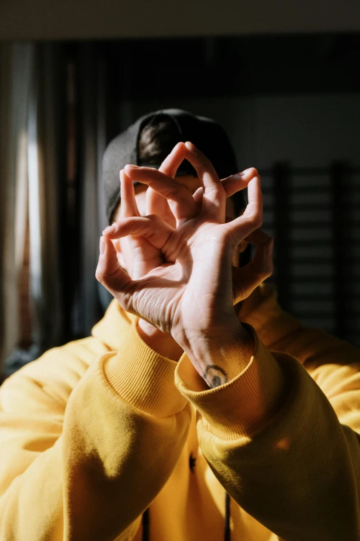 a person making a peace sign with their hands, a picture, by Adam Marczyński, trending on pexels, symmetry!! yellow ranger, esoteric clothing, at home, profile image