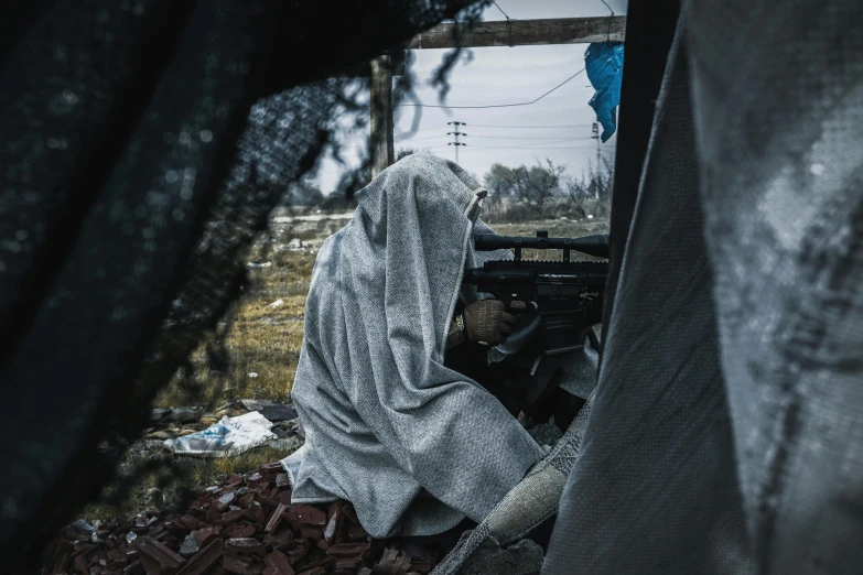 a person sitting in the back of a truck, by Adam Marczyński, grey tarnished robes, makeshift house, balaclava covering face, shot from far away