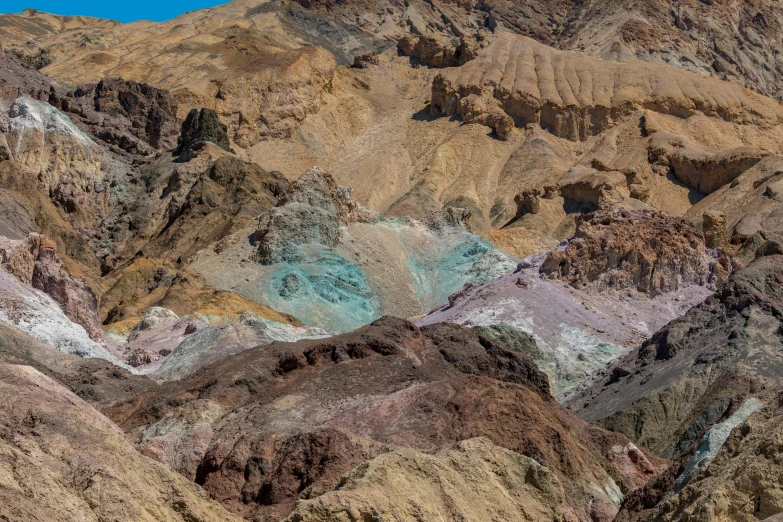 mountains covered in colored rocks, one with a blue, one brown and white substance