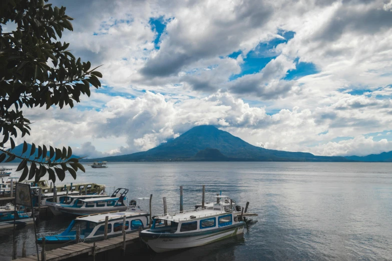 several boats lined up at a pier in front of a mountain