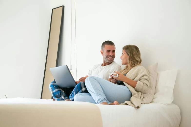 a man and woman sitting on a bed with a laptop, happening, australian, profile image, cozy room, regular build