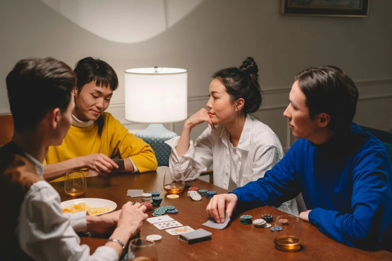 a group of people sitting around a table playing cards, profile image, ignant, board games on a table, at home