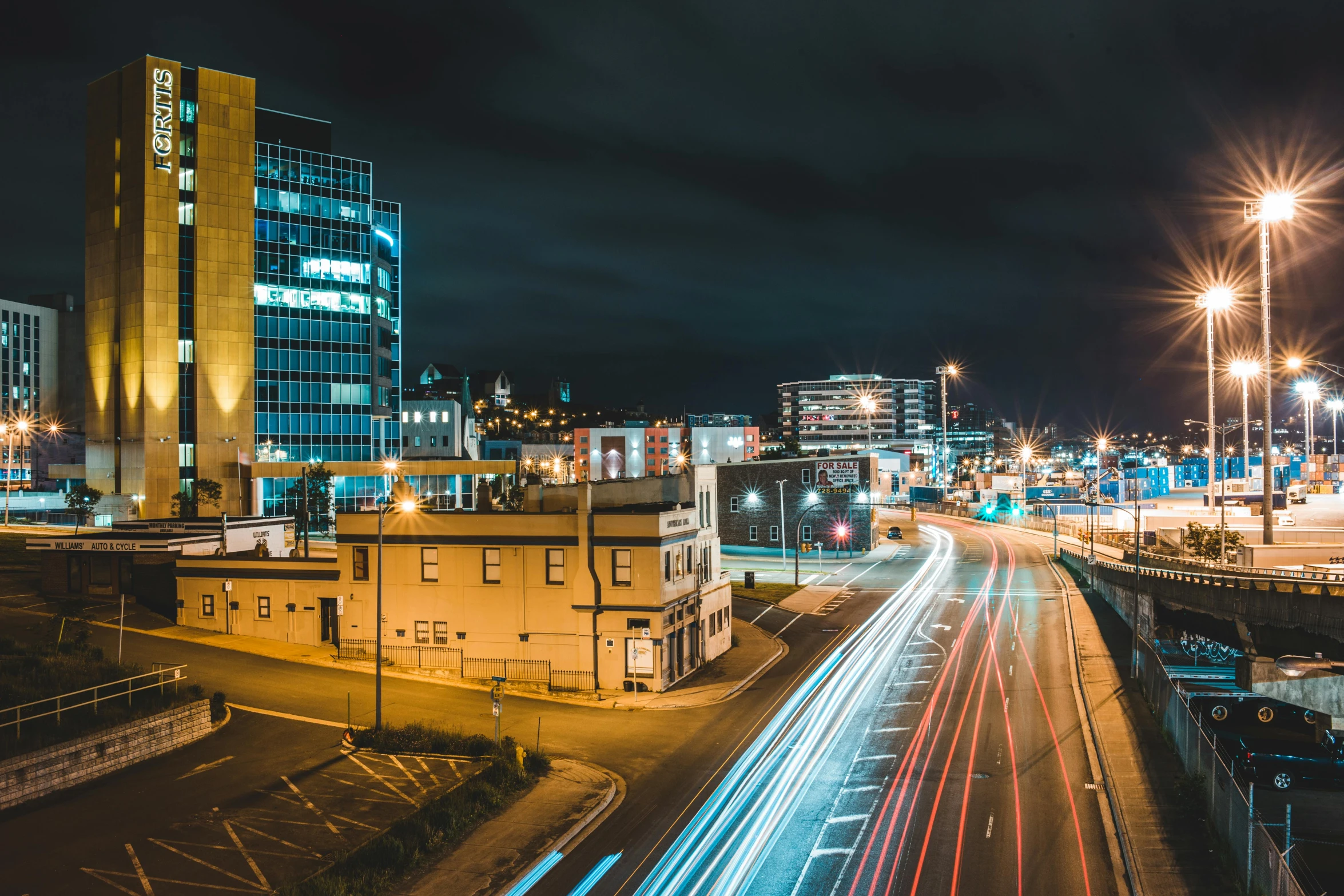 a city street filled with lots of traffic next to tall buildings, by Lee Loughridge, unsplash contest winner, chesterfield, distant town lights, panoramic, dunwall city