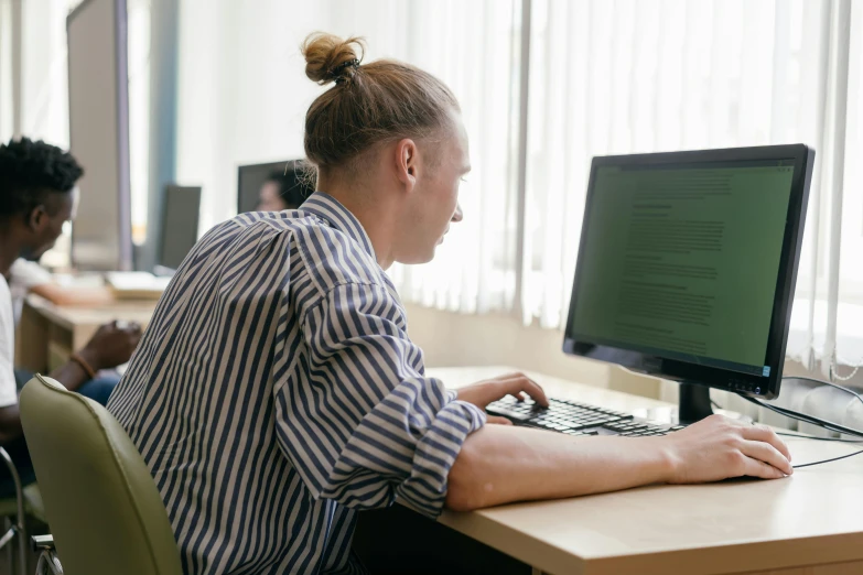 a woman sitting at a desk in front of a computer, unsplash, lachlan bailey, androgynous person, plating, in rows