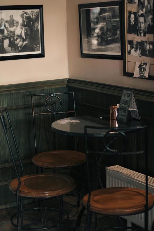 three wooden tables are against a wall with framed pictures on the walls