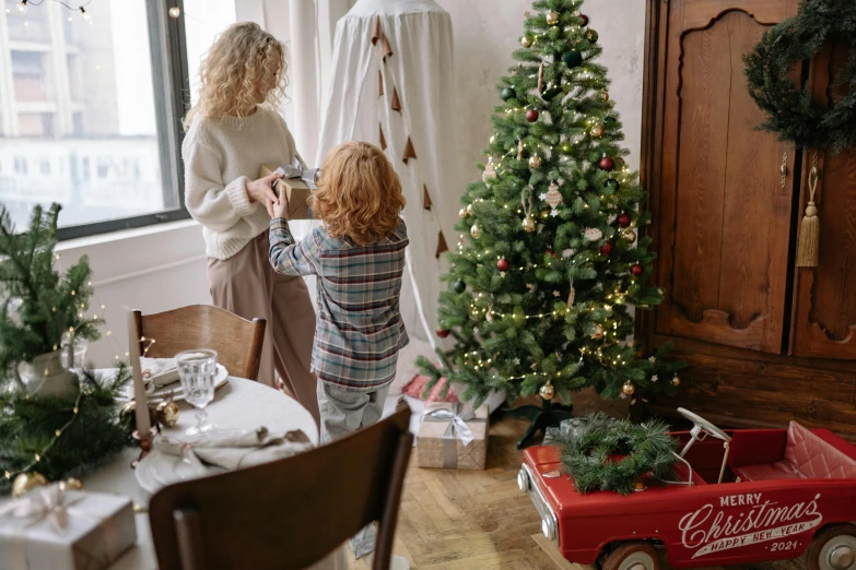 mother and child decorating a christmas tree with gifts