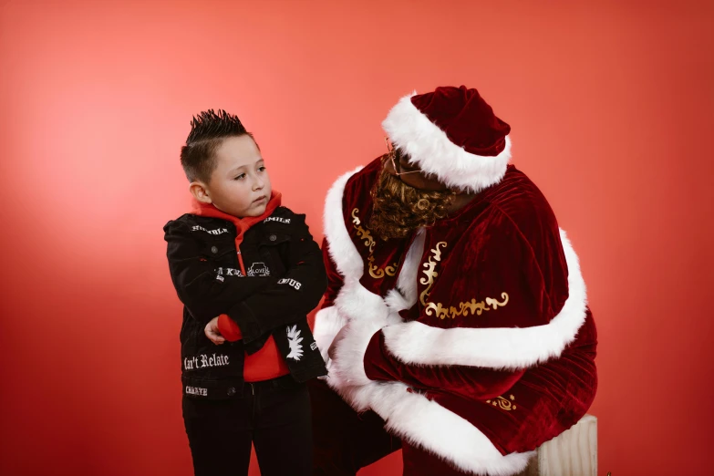 boy in black clothing standing next to large santa clause suit