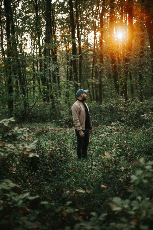 a man standing in the middle of a forest, looking off into the sunset, carson ellis, stylish pose, cinematic shot ar 9:16 -n 6 -g