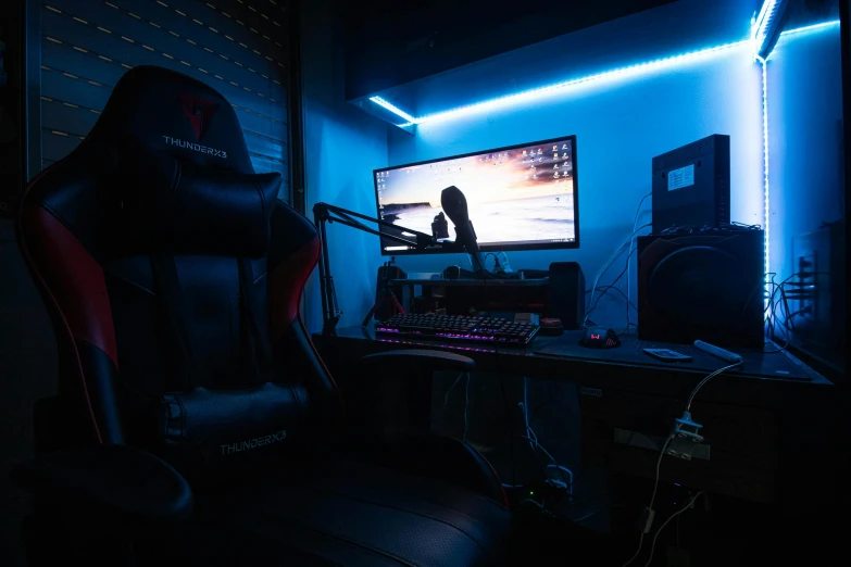computer and monitor in dark room with blue lighting