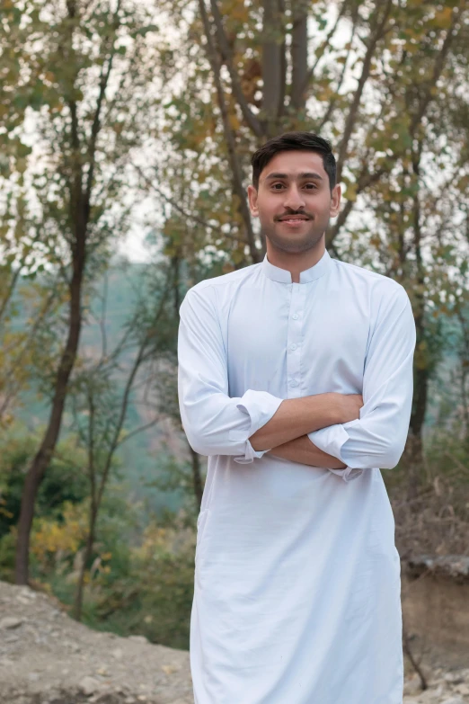 a man standing in front of trees with his arms crossed, by Riza Abbasi, hurufiyya, wearing white clothes, avatar image